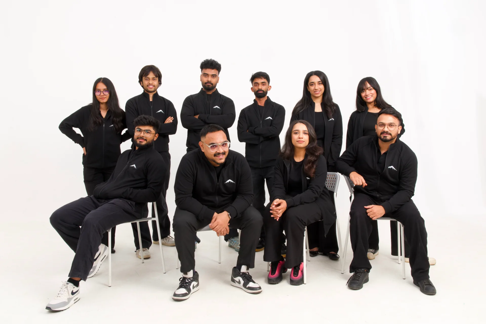 The Lumenridge team, ten people in black, seated and standing together in the studio